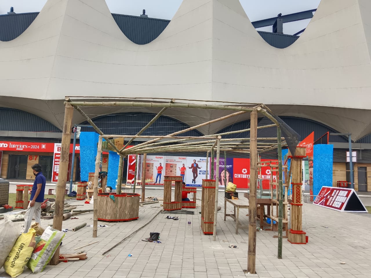 Daytime — mid-construction bamboo frame with convention centre behind